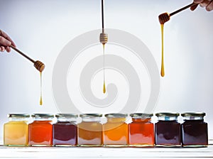 Jars of honey, and sticks spilling honey on white background