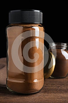 Jars of instant coffee on wooden table, closeup