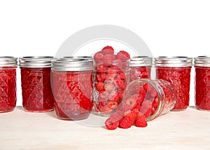 Jars of jam with fresh raspberries on wood table