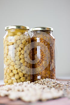 Jars of non-perishable chickpeas and lentils with spilled seeds on the table