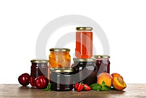 Jars of pickled fruits and jams on grey table