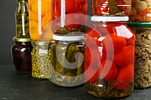 Jars of pickled vegetables on grey table, closeup