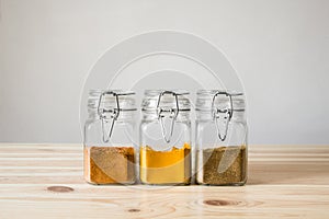 Jars with spices on light wood table.