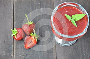 Jars of strawberry jam or jelly with berries and spoon on brown woodwn background close up top view, copy space.