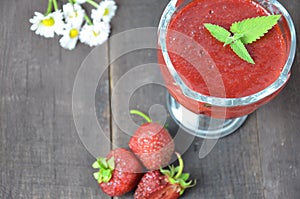 Jars of strawberry jam or jelly with berries and spoon on brown woodwn background close up top view, copy space.