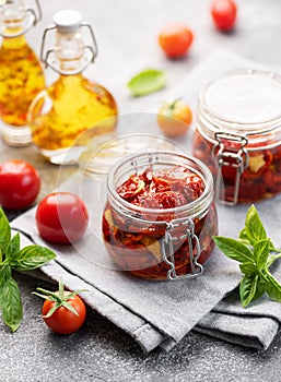 Jars with sun dried tomatoes with fresh herbs and spices