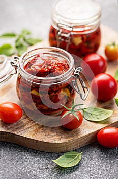 Jars with sun dried tomatoes with fresh herbs and spices