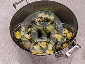 Jars of vegetables in a large aluminum pan. pasteurization of canned vegetables photo