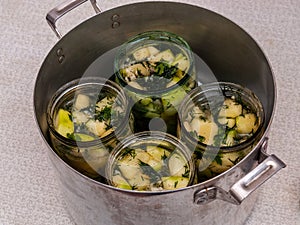Jars of vegetables in a large aluminum pan. pasteurization of canned vegetables