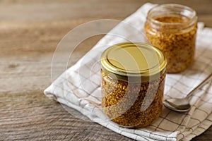 Jars of whole grain mustard on wooden table. Space for text