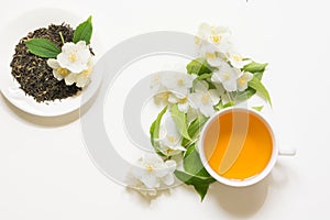 Jasmine dry green tea leaves with fresh jasmine flowers and cup of tea on white background.