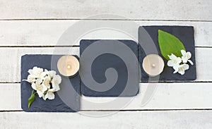 Jasmine flowers and candles on wooden table, on stone stands