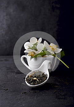 Jasmine flowers and cup of healthy tea  on a black background. Green tea with jasmine. Herbal medicine