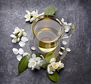 Jasmine flowers and cup of healthy tea, herbal medicine. A cup of green tea with jasmine on a black background