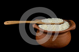 Jasmine rice in a clay pot and the wood ladle on white background