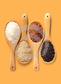 Rice in wooden ladle on yellow orange color background top view with clipping path.