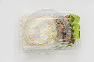 Jasmine rice with spicy pork fried with hot basil and fried egg in a transparent plastic box package