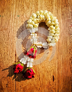 Jasmine with rose garlands lay on the wooden desk.