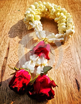 Jasmine with rose garlands lay on the wooden desk.