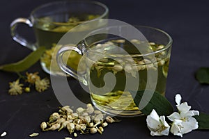 Jasmine tea. two cups of hot herbal tea with linden flowers on a black table