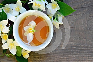 Jasmine tea in a white cup with fresh jasmine flowers on old wooden table.Healthy drink,diet or herbal medicine concept.