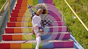Jaunty young woman sitting on rainbow steps