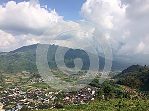 Java, Indonesia. A view from the mountain road on hills with green fields and the village in the valley
