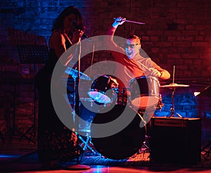 Jazz band performance. Couple of musicians - a drummer and a singer in a nightclub.