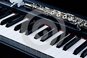 Jazz music instrument flute and piano keyboard close up with flower