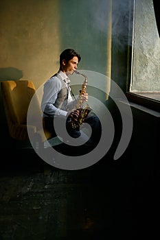 Jazz musician playing saxophone in front of window