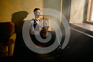 Jazz musician playing saxophone front of window