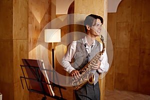 Jazz musician playing saxophone and leaning against art studio wall