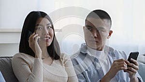 Jealous Asian Husband Looking At Wife Talking On Phone Indoor