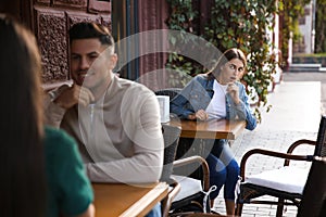 Jealous ex girlfriend spying on couple in outdoor cafe