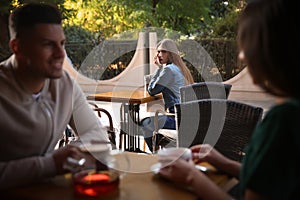 Jealous ex girlfriend spying on couple in outdoor cafe