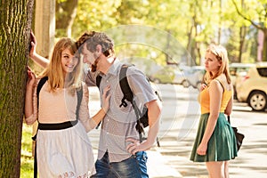 Jealous girl looking at flirting couple outdoor.