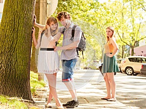 Jealous girl looking at flirting couple outdoor.