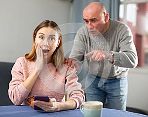 Jealous husband looking at his wife using smartphone