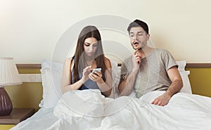 Jealous husband watching his wife mobile phone on the bed