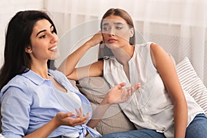 Jealous Woman Listening To Friend Bragging Sitting On Sofa Indoor photo