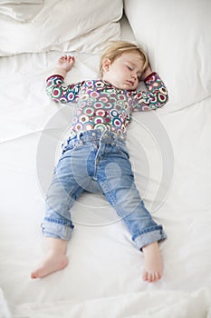 Jeans baby sleeping on white bed