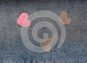 Jeans background with pink and glitter silver hearts. Blue jeans cloth. Valentine`s Day. Teenage style