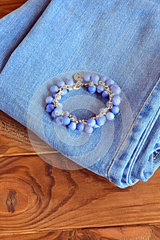 Jeans, bracelet on wooden background with copy space for text