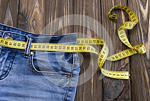 Jeans, centimeter on a wooden background