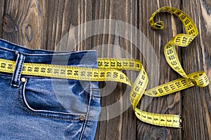 Jeans, centimeter on a wooden background.