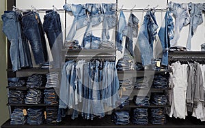 Jeans denim trousers and shirts hanging or arranged on the shelf of a clothing store photo