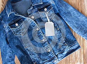 Jeans female jacket on wooden background with tag label.