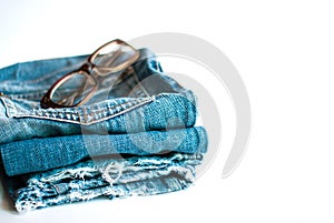 Jeans folded and glasses on a white background.