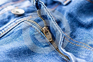 Jeans front with zipper open. Bright blue denim fabric texture background