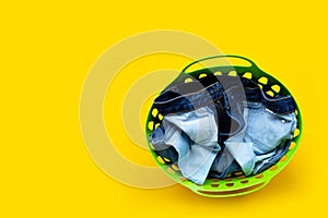 Jeans in green laundry basket on yellow background